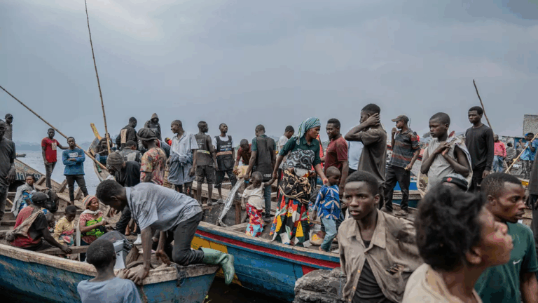Survivors and local residents gather near wooden boats along the Congo River following a maritime disaster, waiting for rescue or aid.