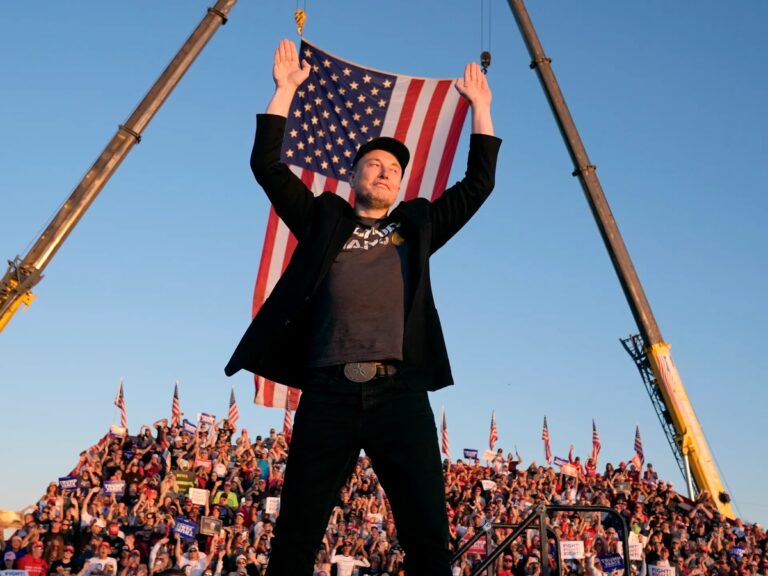 Elon Musk raising his arms at a political rally with a large American flag behind him, symbolizing his leadership role in DOGE taxpayer savings claims.