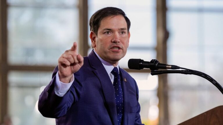 U.S. Secretary of State Marco Rubio delivering a speech at a podium, gesturing while addressing the audience.