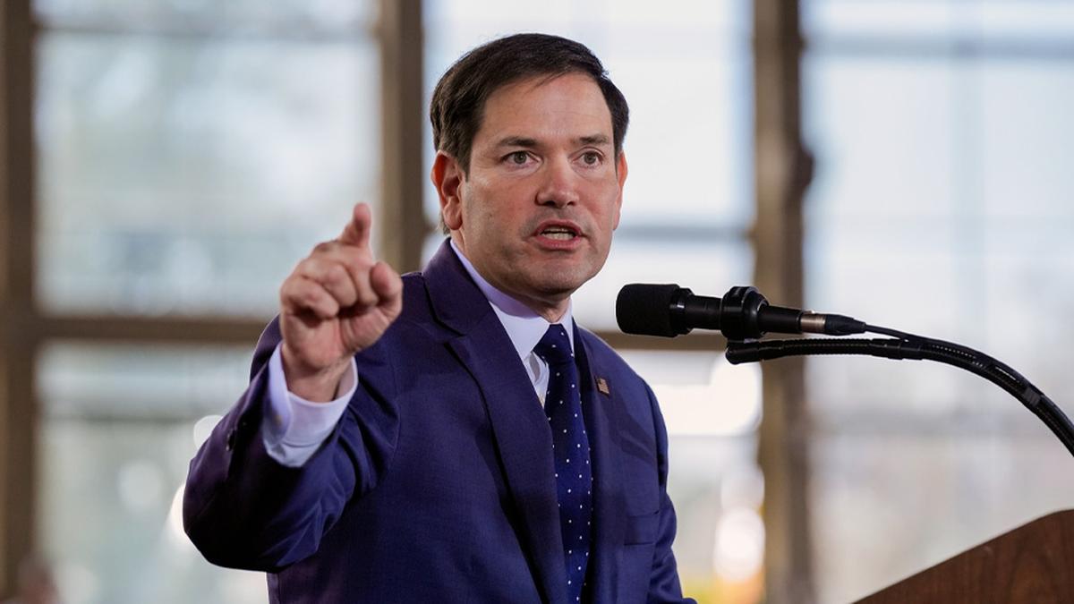 U.S. Secretary of State Marco Rubio delivering a speech at a podium, gesturing while addressing the audience.