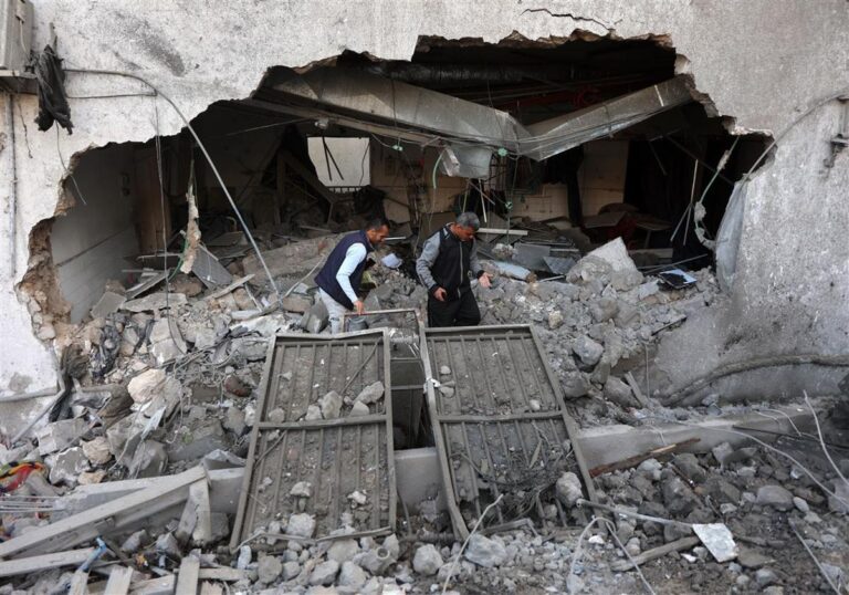 Two men inspect the rubble of Al-Ahli Baptist Hospital after an Israeli airstrike in Gaza City, April 2025.