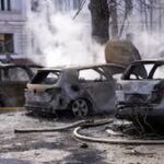 Burned and smoking cars line a street in Ukraine following a missile strike.