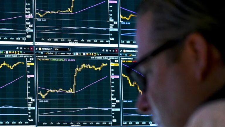 Trader watches stock charts spike after Trump pauses tech tariffs, easing market fears.