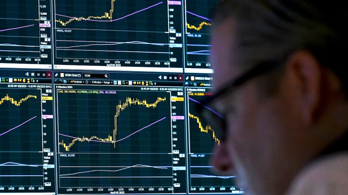Trader watches stock charts spike after Trump pauses tech tariffs, easing market fears.