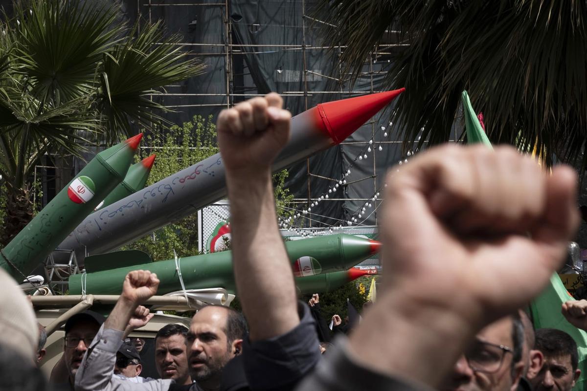 Protesters raise fists in front of mock Iranian missiles during a demonstration in Tehran, symbolizing resistance amid nuclear tensions.