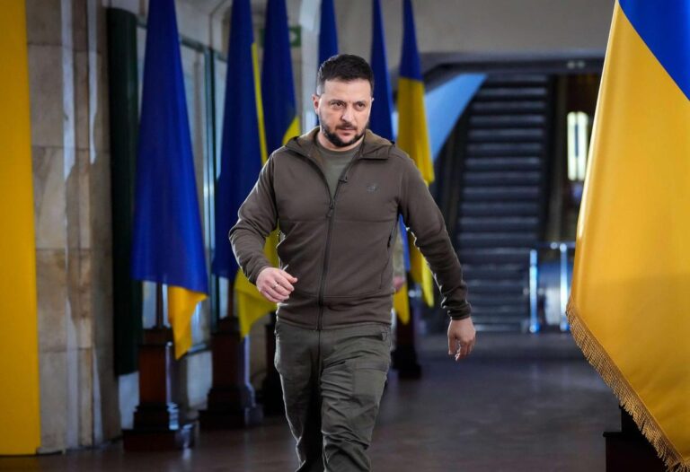 Ukrainian President Volodymyr Zelenskyy walks through a hallway lined with Ukrainian flags after announcing sanctions against Chinese companies.