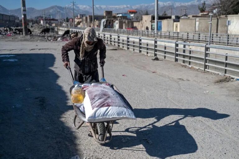 A man pushes a wheelbarrow loaded with food supplies through Kabul, underscoring the daily realities of the Afghanistan humanitarian crisis.