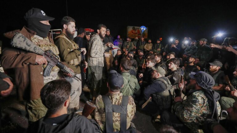 Armed fighters gather at night amid rising tensions after Israeli airstrikes on Syrian territory